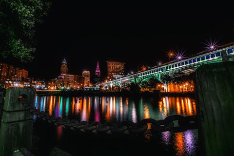 a night shot of a Cleveland bridge, with colorful lights reflecting in the water