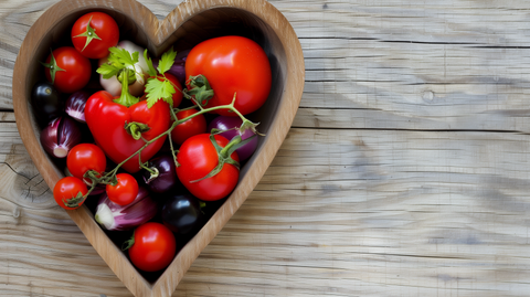 a heart shaped wooden bowl with bell peppers, onion, and tomato