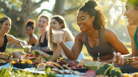 a diverse group of women in athletic wear, joyfully enjoying a picnic with a variety of protein-rich foods like grilled chicken, tofu, beans, nuts, and protein shakes, in a sunny park setting