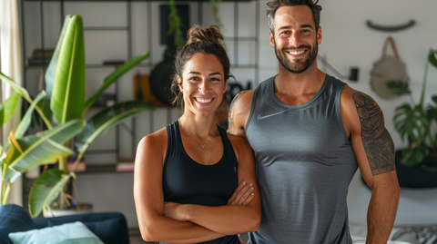 a fit man and woman standing side by side in their living room wearing athletic clothes and smiling