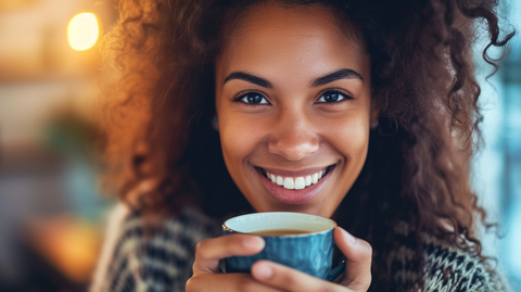a girl smiling, holding a cup of tea
