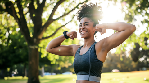  a fit young woman standing at the park flexing her arms and smiling toward the camera